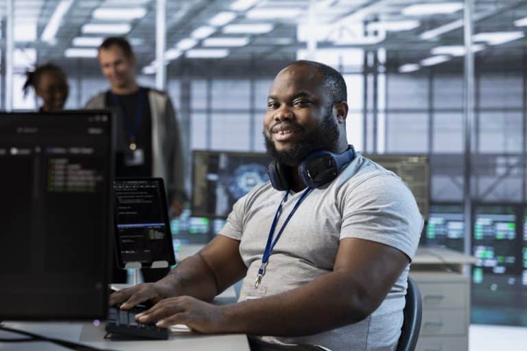 IT support engineer working at a computer in a modern operations room, representing internal service requests, troubleshooting, and IT support workflows.